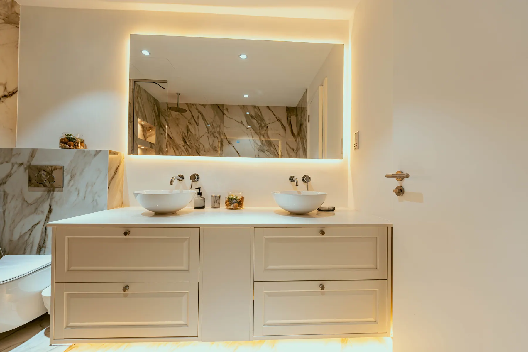 Twin marble vanities with a backlit mirror