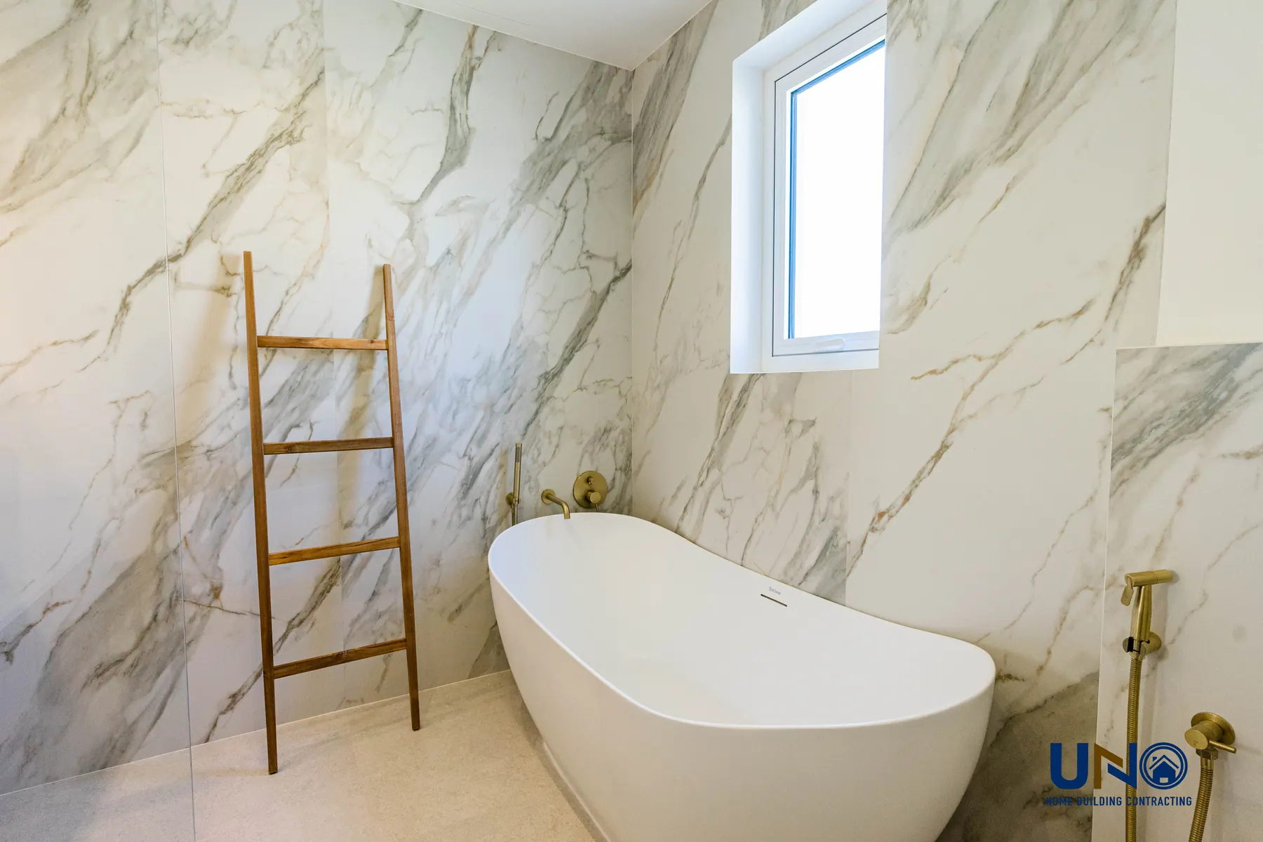 Marble bathroom with a freestanding tub and brushed brass fittings in Jumeirah Village Triangle