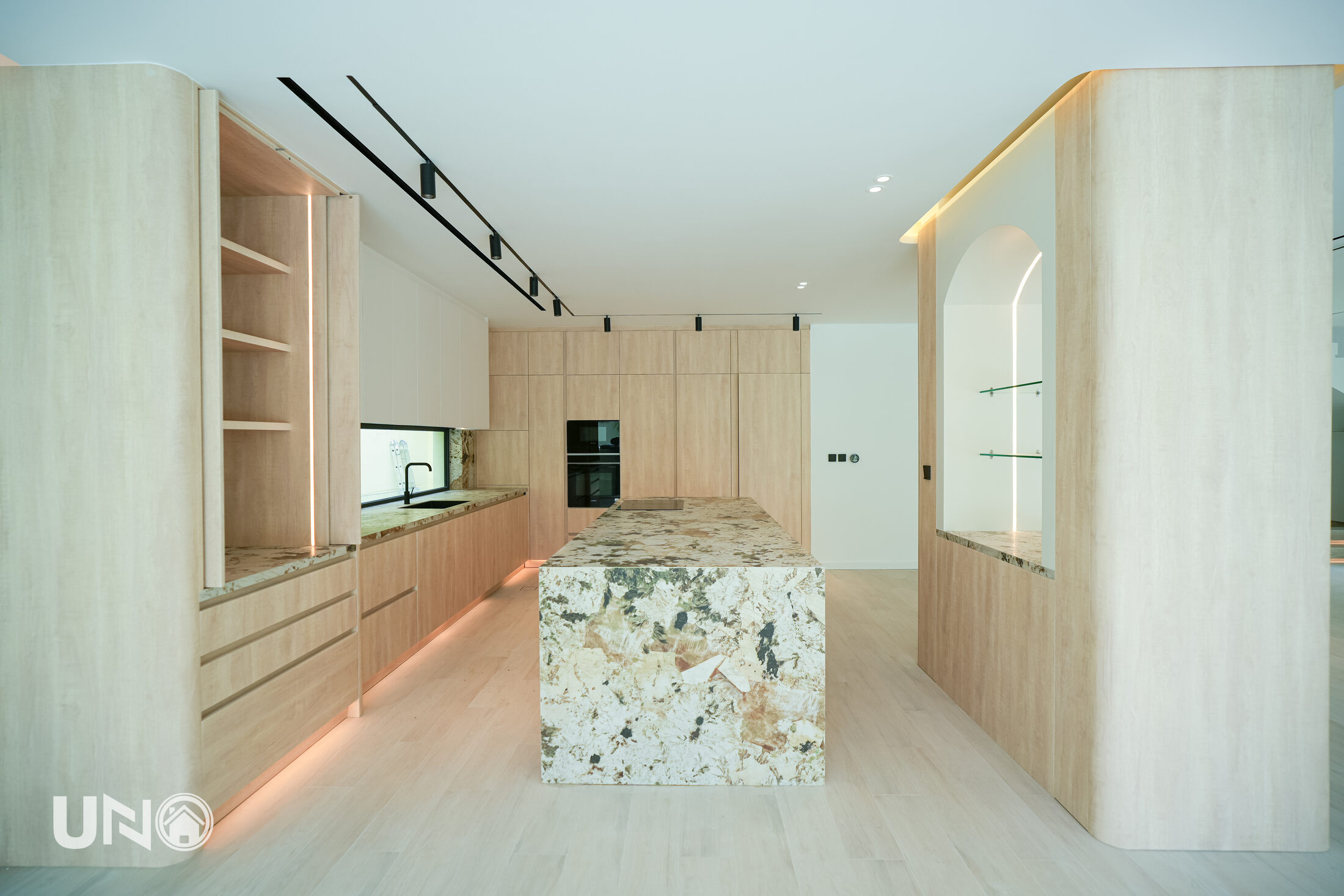 Warm oak kitchen with veined marble island opening to garden